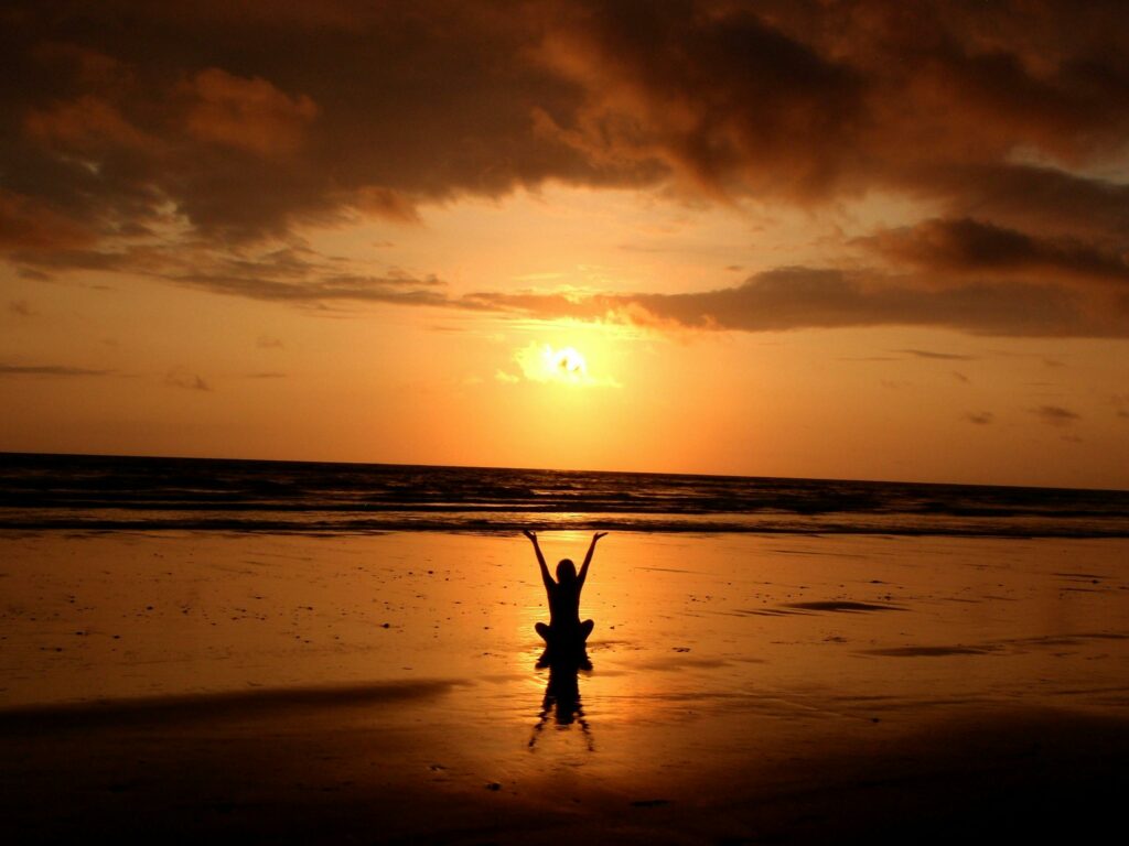 Illustration d'une femme à la plage au coucher du soleil en train de pratiquer la méditation. 