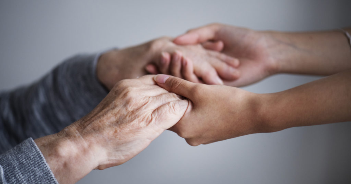 Photo de mains d'une personne âgée et d'une personne adulte se tenant les mains.