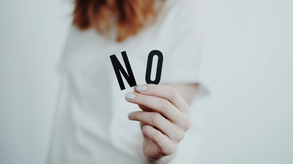 Une femme qui montre les lettres N et O pour dire non. 